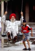 A Sikh child pushes his grandfather on a swing in a park in the northern Indian city Chandigarh August 13, 2006. REUTERS/Kamal Kishore (INDIA)